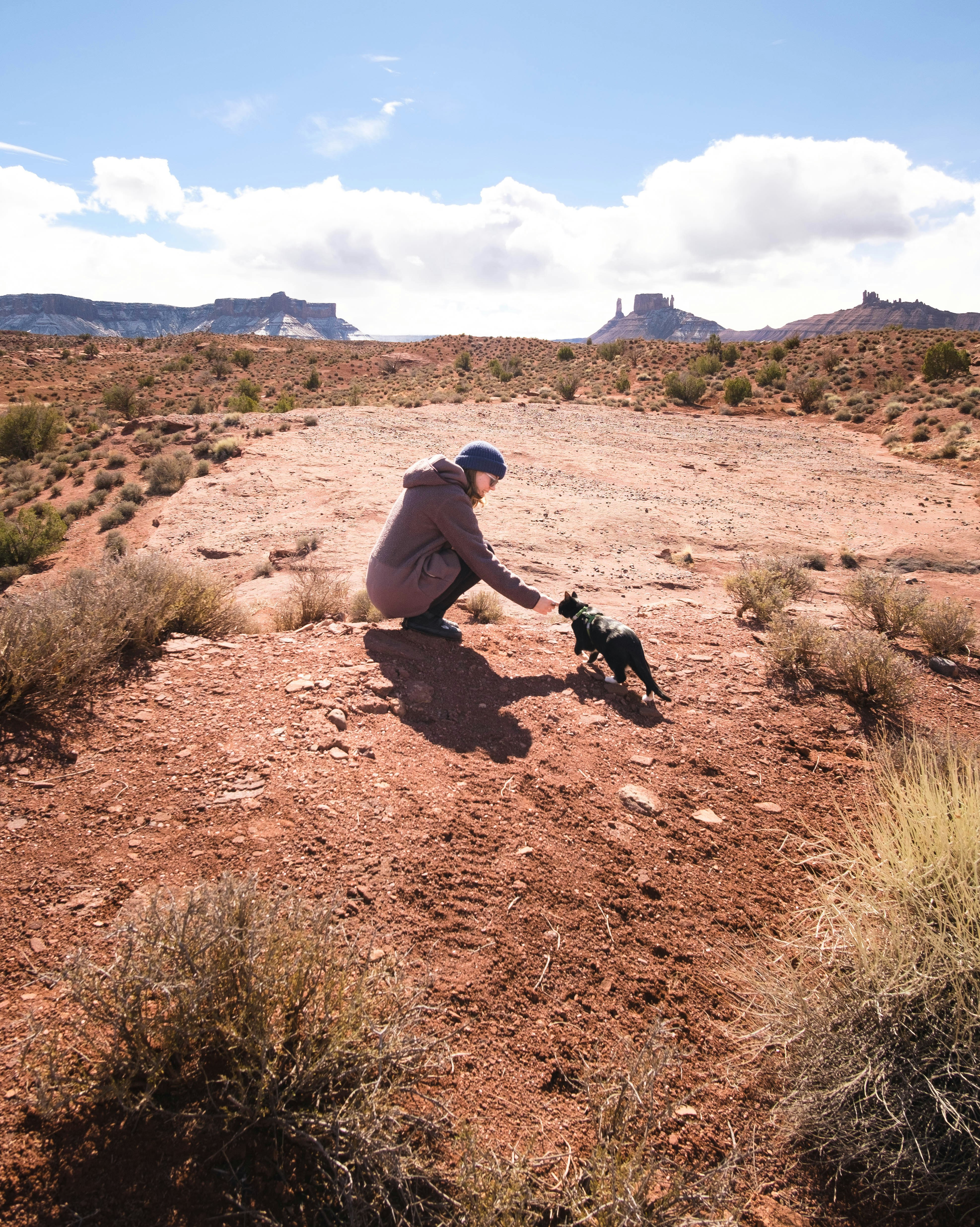 man in gray hoodie and black pants sitting on brown dirt road during daytime